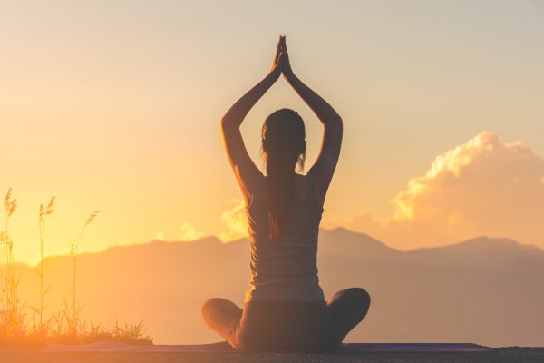 silhouette fitness girl practicing yoga on mountain with sun light